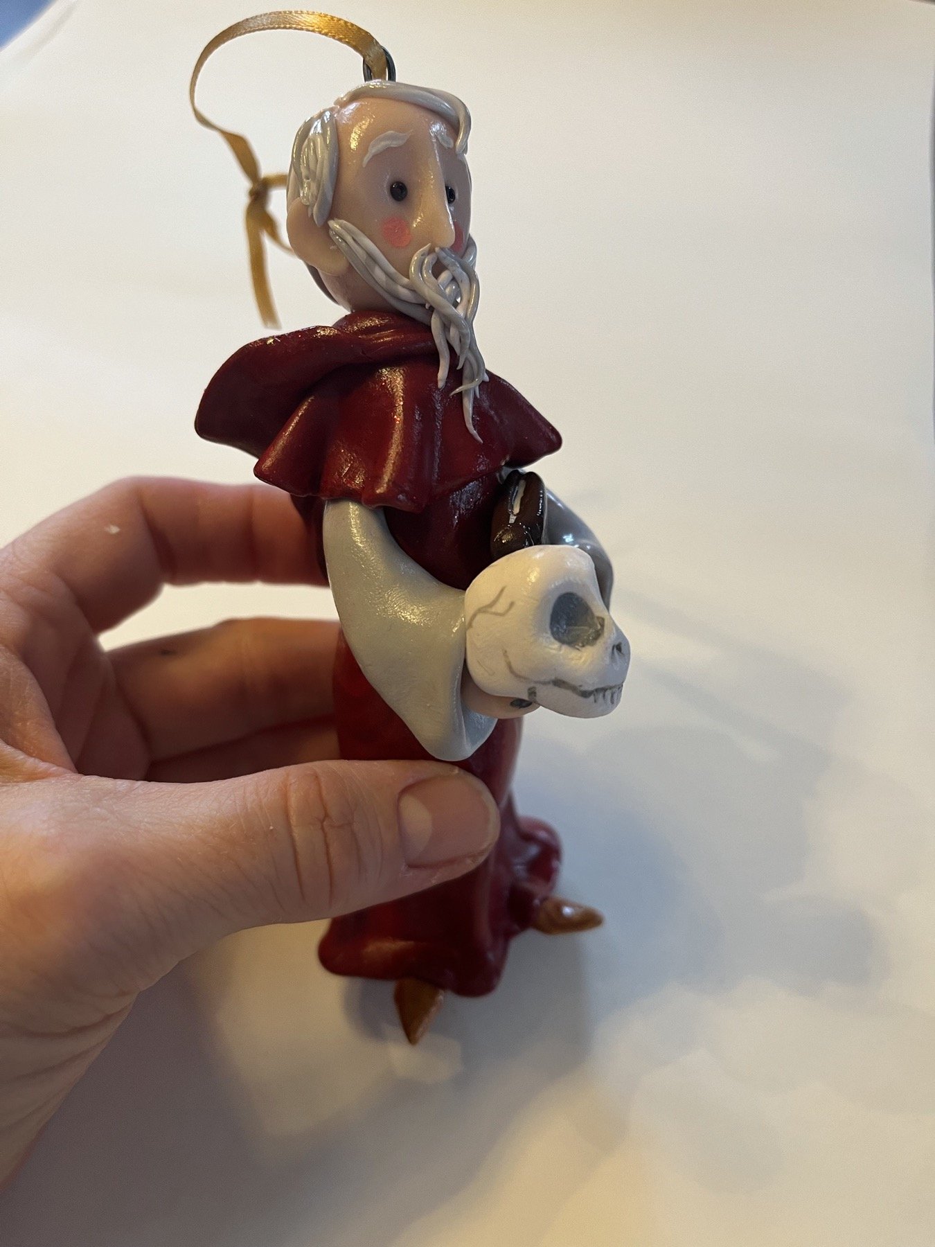 Side view of a hand-sculpted saint figure in a red robe